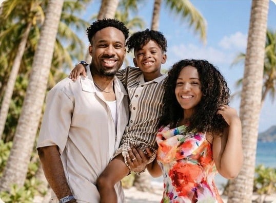 Sasha and Anthony with their son on a tropical beach